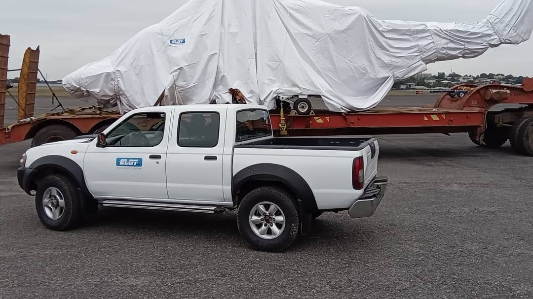 Véhicule pilote ouvrant la route devant un porte-engins bâché